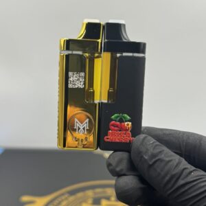 Hand holding the connected Muha Meds Gen 2x2 Magnets 4G hardware showing the gold logo and Ibiza Cherry branding